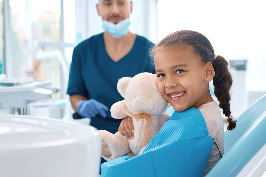 Little girl visiting the dentist and looking into a mirror